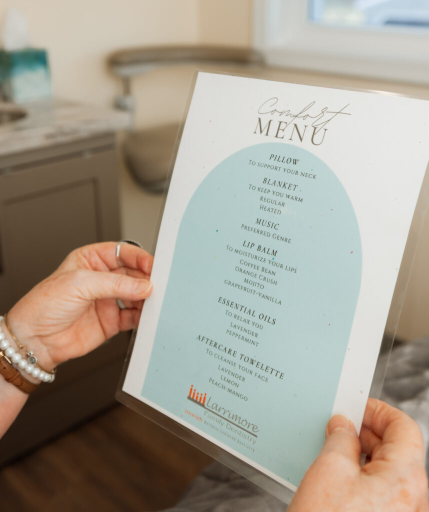 A staff member holding the Larrimore Family Dentistry "Comfort Menu"