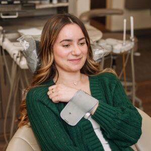 Female dental patient smiling with blood pressure cuff on arm