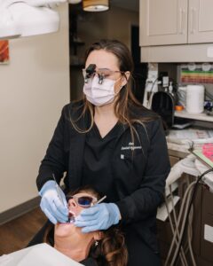 Dental hygienist performing a cleaning on a patient wearing protective glasses