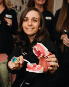 Dental hygienist demonstrating brushing technique on a mouth model