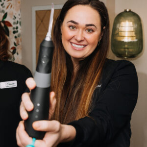 Smiling woman showing a water flosser to the camera