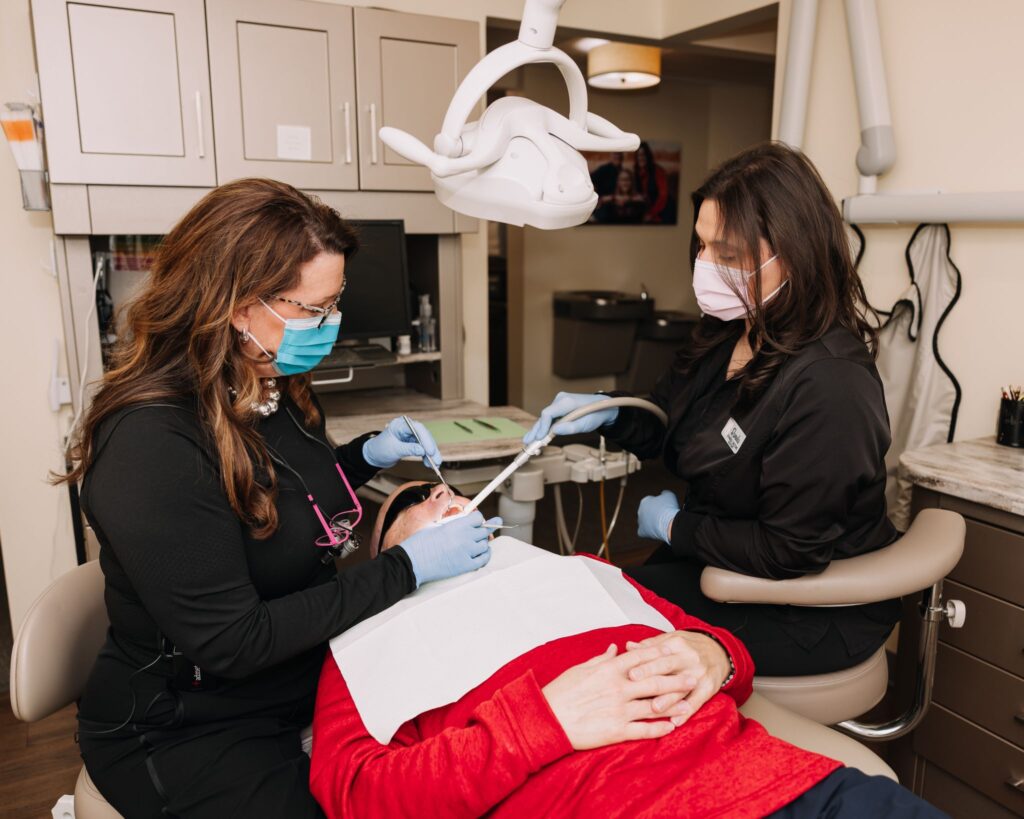 Dental team providing treatment to a seated patient