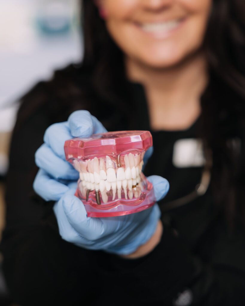 Dental implant model demonstrating tooth replacement options compared to saving a natural tooth