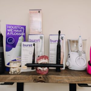 Collection of oral hygiene tools including electric toothbrushes, water flosser, and dental models