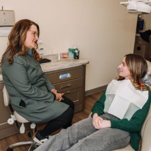 Dentist discussing sports mouthguard protection with a patient in the dental chair