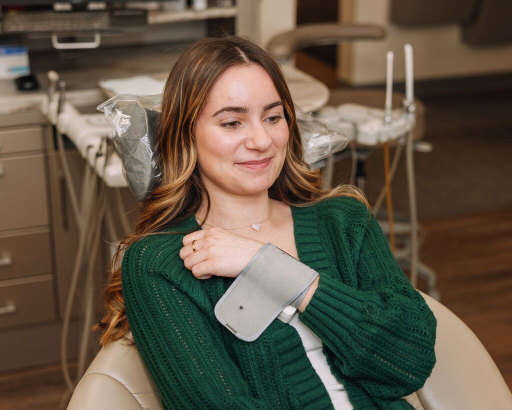 Dental patient seated in a treatment room with a blood pressure cuff on her arm
