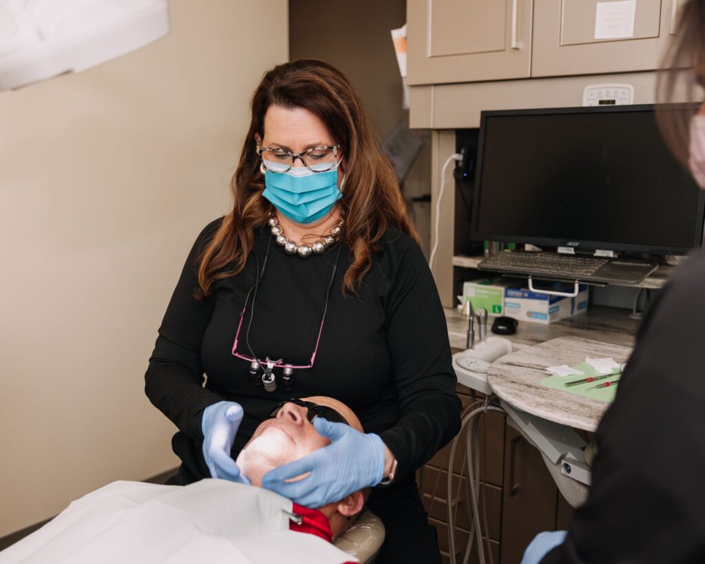 Masked dental professional caring for a patient in the dental chair