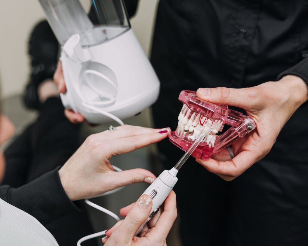 Water flosser being demonstrated on a dental model to show cleaning around the teeth and gums