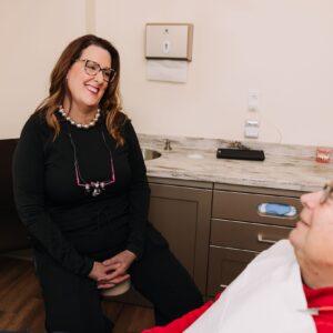 Dental professional talking with an older adult patient in a treatment room